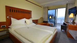 Una habitación de hotel con una cama grande, un escritorio, una silla y un balcón con vistas.
