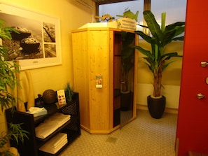 A wooden sauna room with a wooden bench, a shelf with towels, and a potted plant. - Trip Inn Landhotel Bad Soden-Salmünster (Bad Soden-Salmuenster)