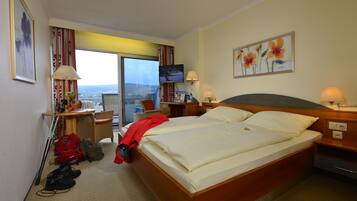 A hotel room with a bed, a desk, a chair, a TV, and a window with a view.