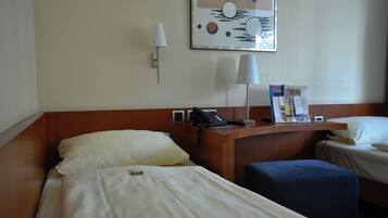 Une chambre d’hôtel avec deux lits, un bureau doté d’un téléphone, une lampe et une œuvre d’art accrochée au mur.