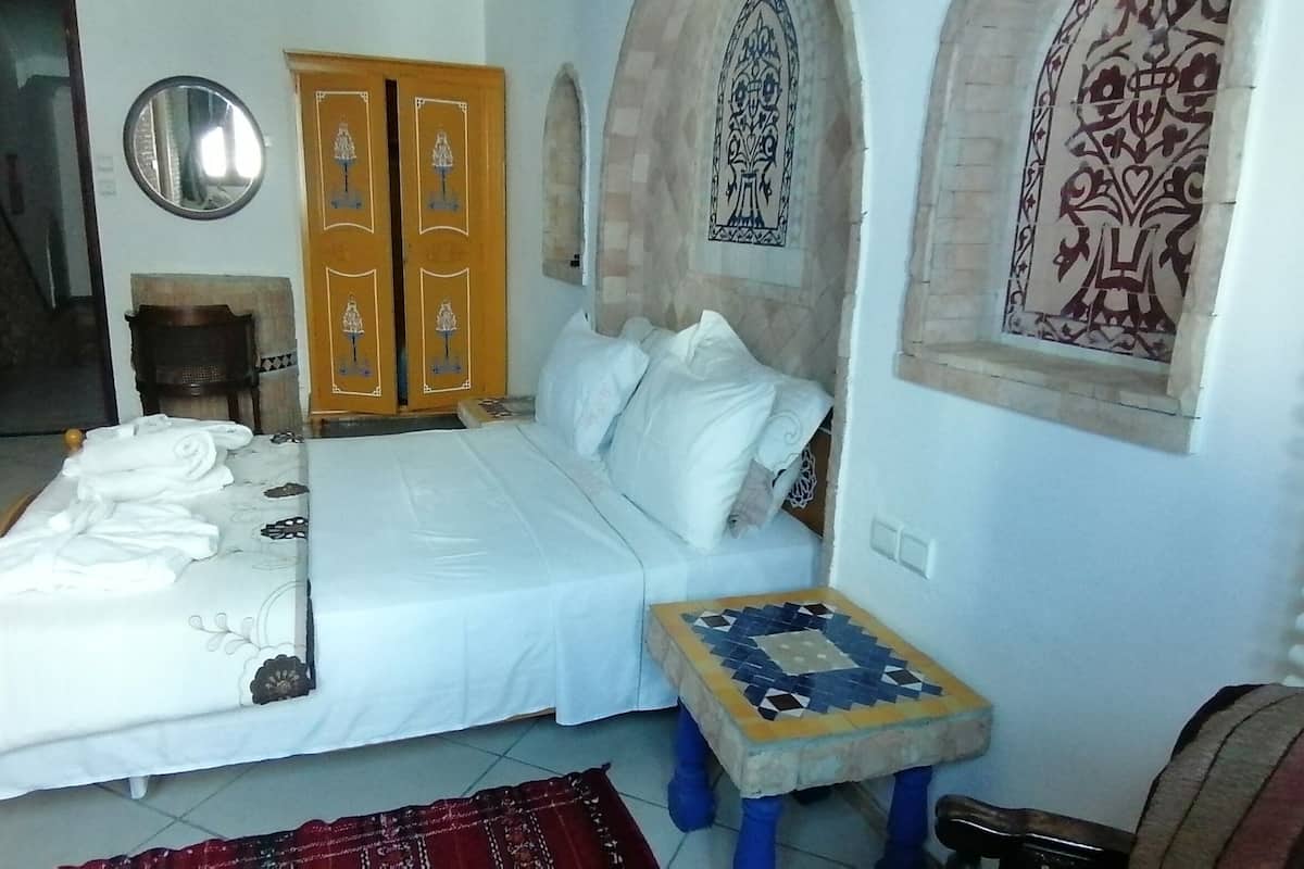 Un dormitorio con cama, una mesita, un armario y un espejo.