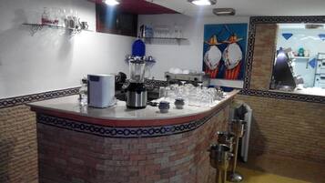 Una zona de bar con mostrador de ladrillo, una máquina de café y varios vasos.