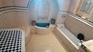 Un baño con azulejos estampados, un lavamanos y un espejo.