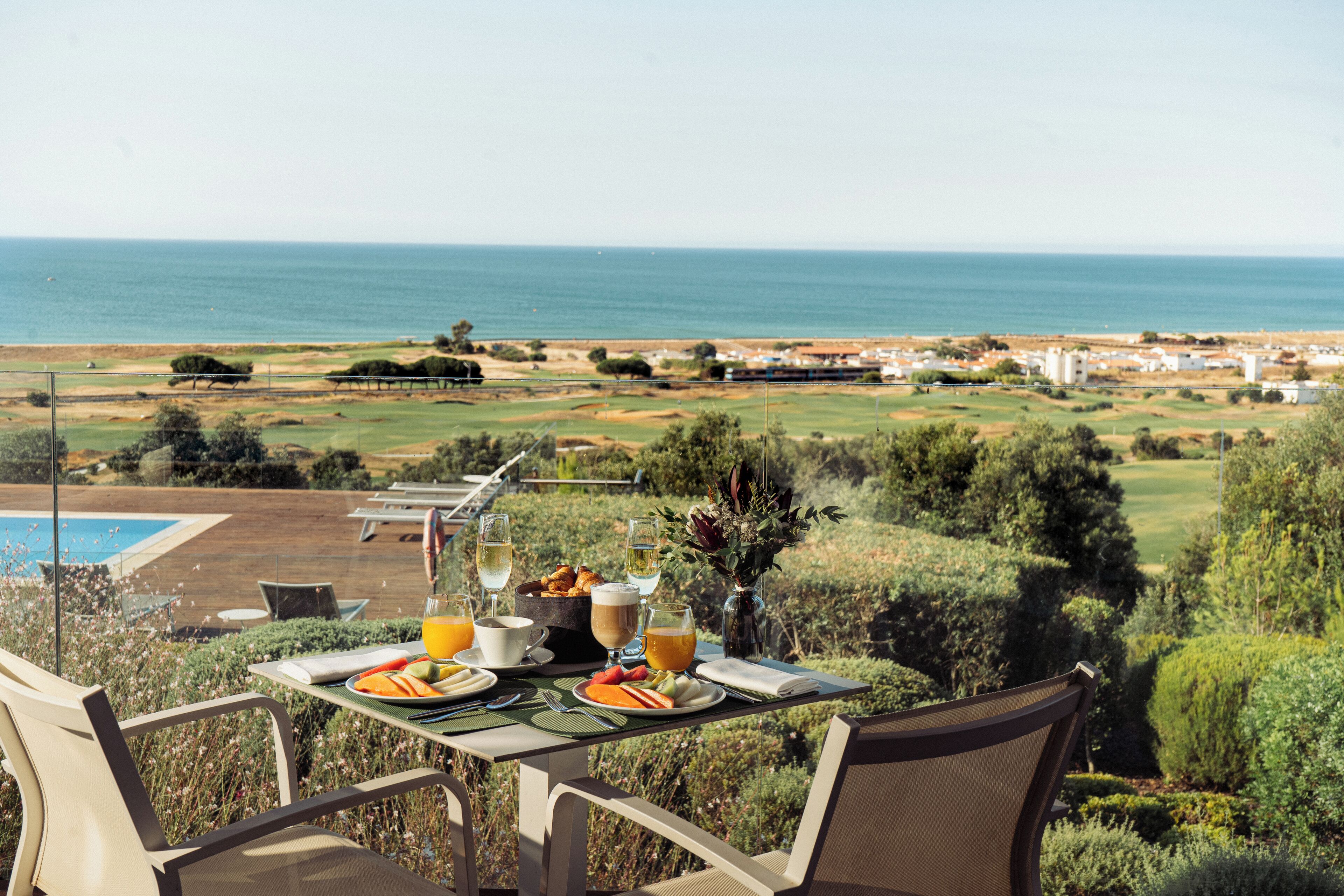 A dining table with breakfast items and a view of the ocean and golf course.