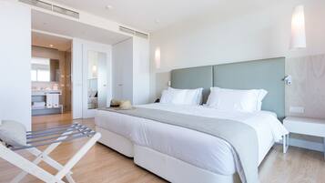 A modern hotel room with a large bed, a bedside table, a wall-mounted light, and a view into the bathroom.