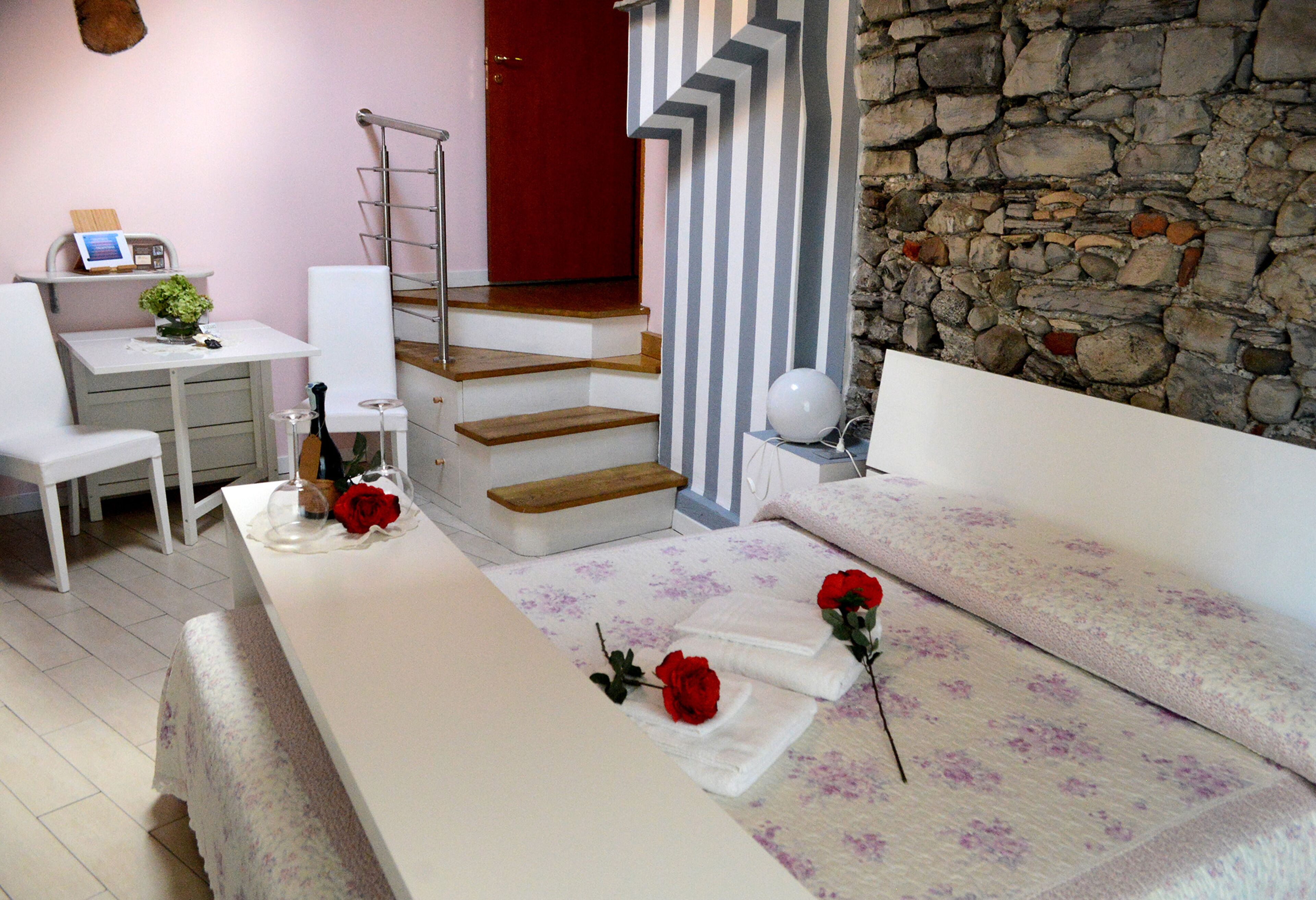 Un dormitorio con una cama, un escritorio, una silla, una escalera y una pared de piedra.
