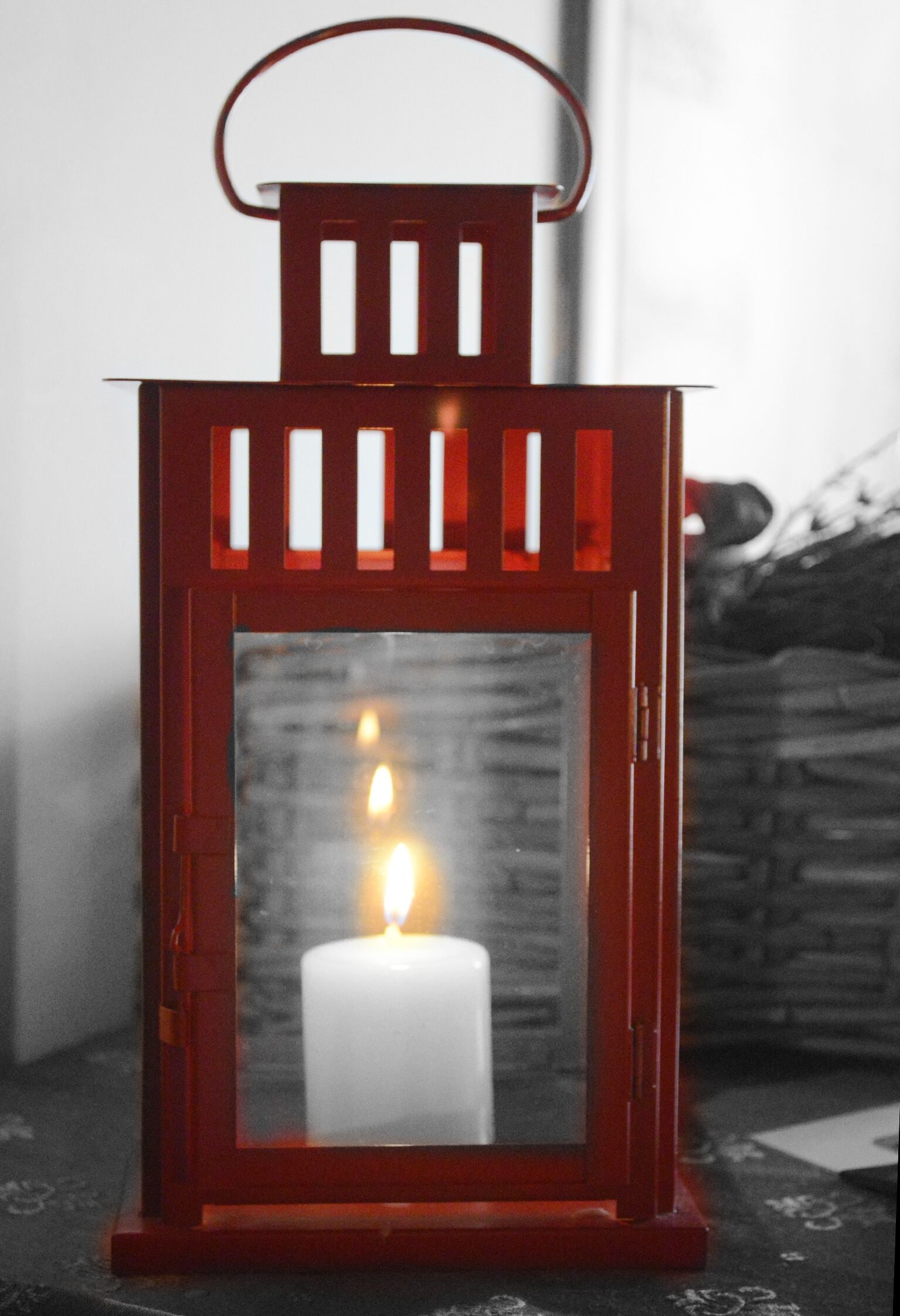 A red lantern with a candle inside, placed on a patterned surface.