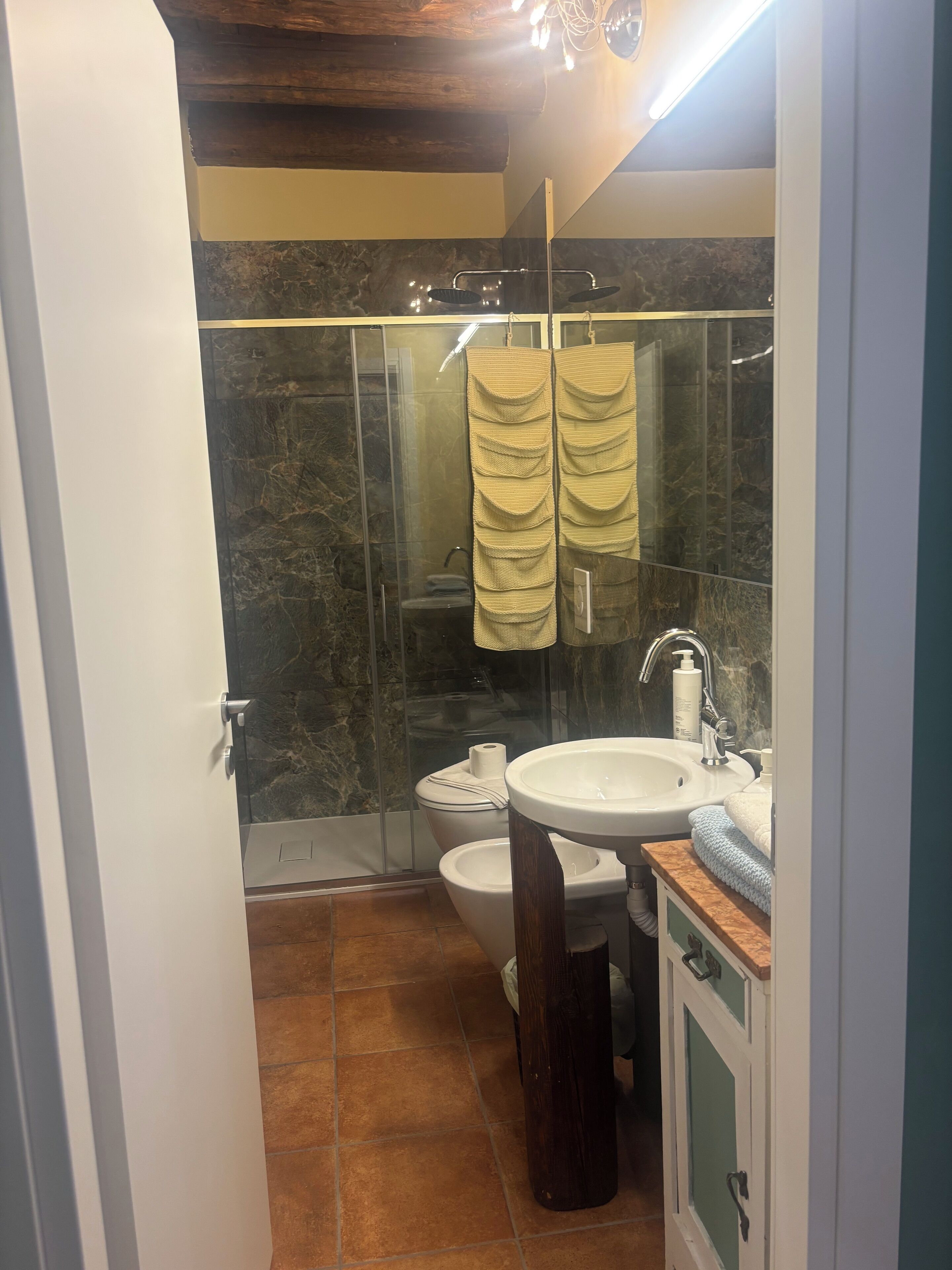 A compact bathroom with a glass shower enclosure, a toilet, and a sink with a mirror.