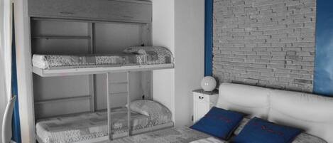 A room with a bunk bed, a bedside table with a lamp, and a brick-patterned wall.