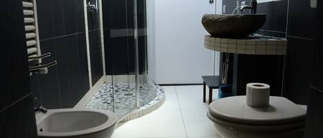 A bathroom with a bidet, a toilet, a sink, and a shower.