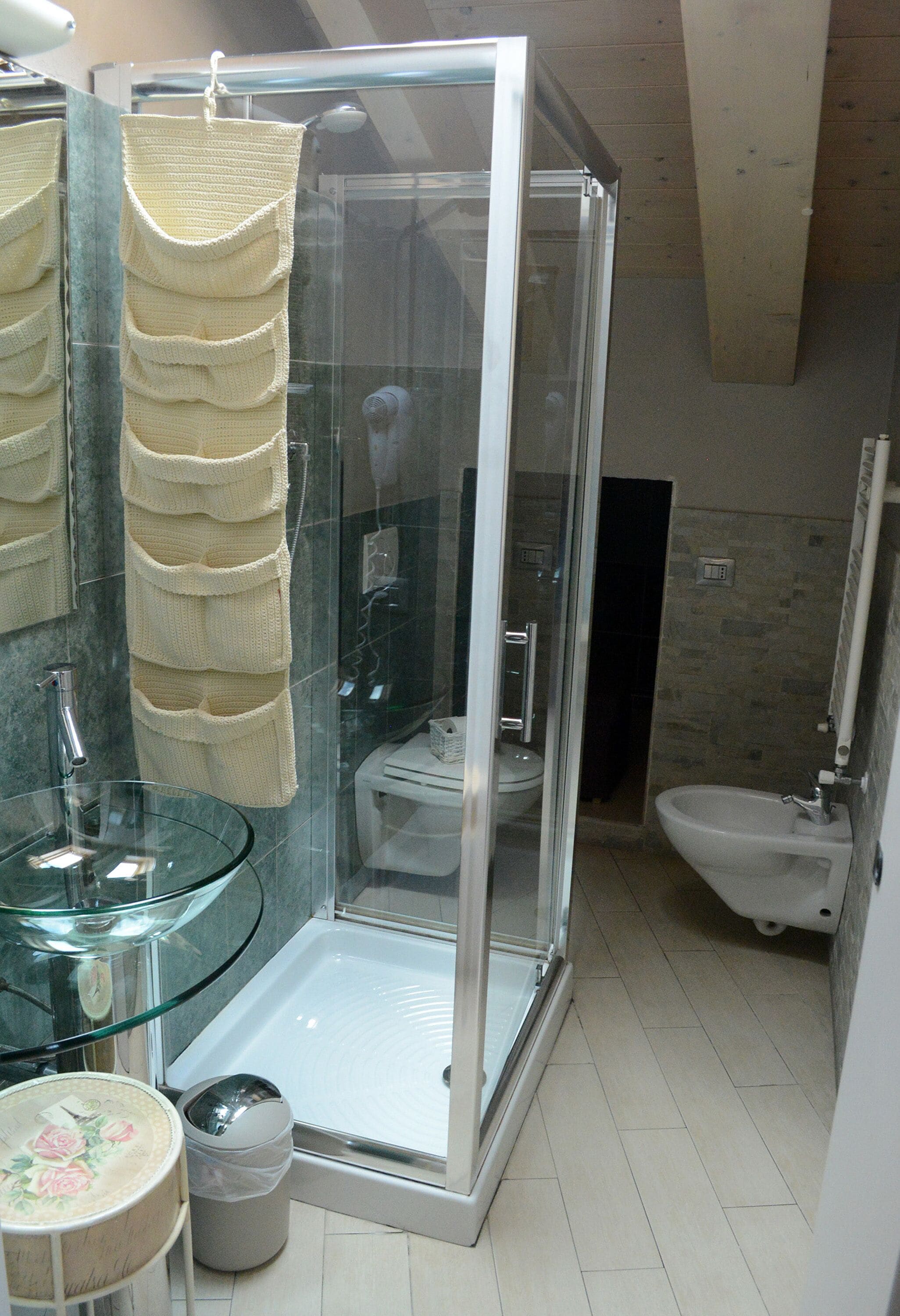 A modern bathroom with a glass-enclosed shower, a glass sink, and a bidet.