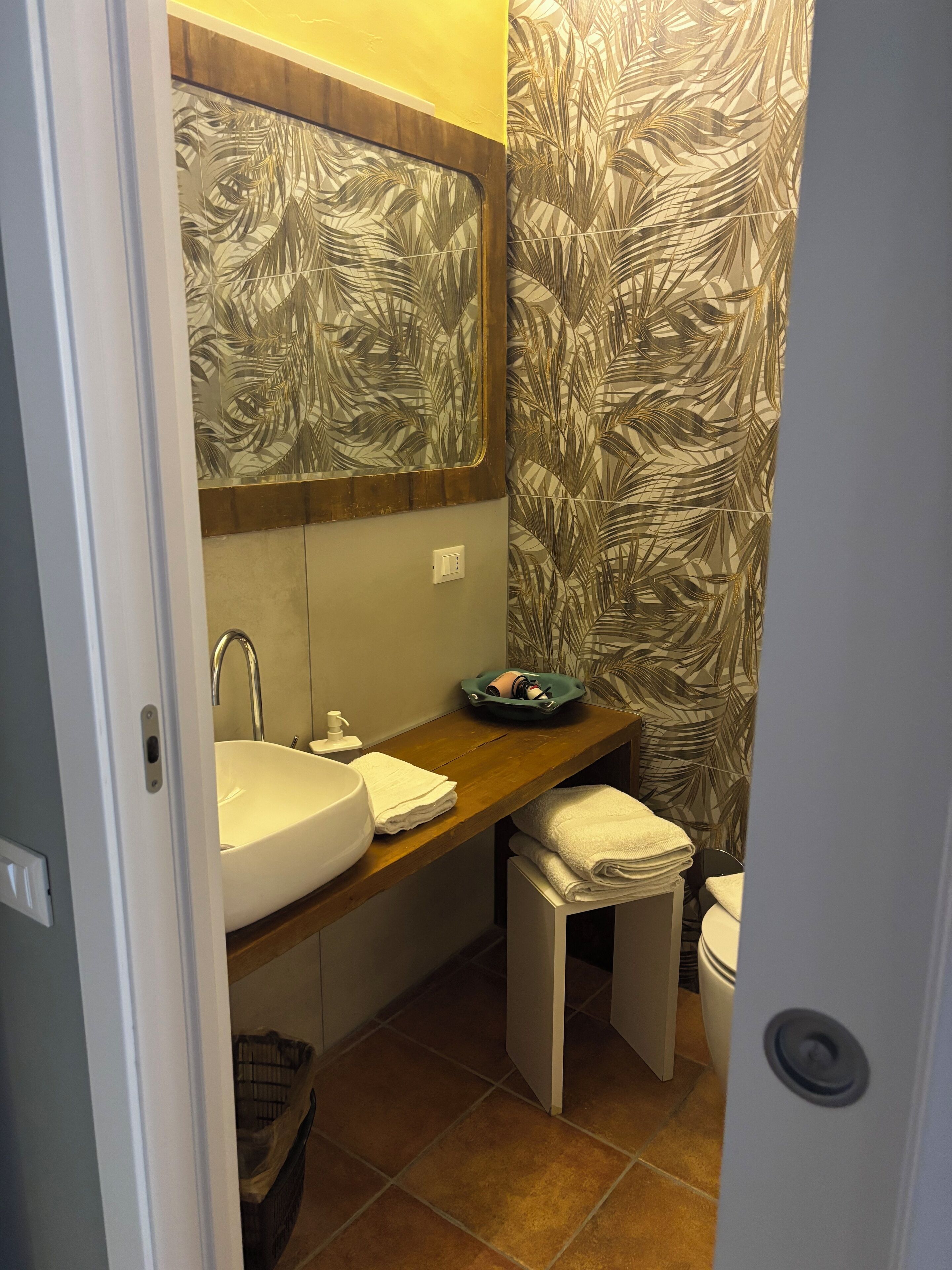 Une petite salle de bain avec un lavabo blanc, un miroir au-dessus et des toilettes.