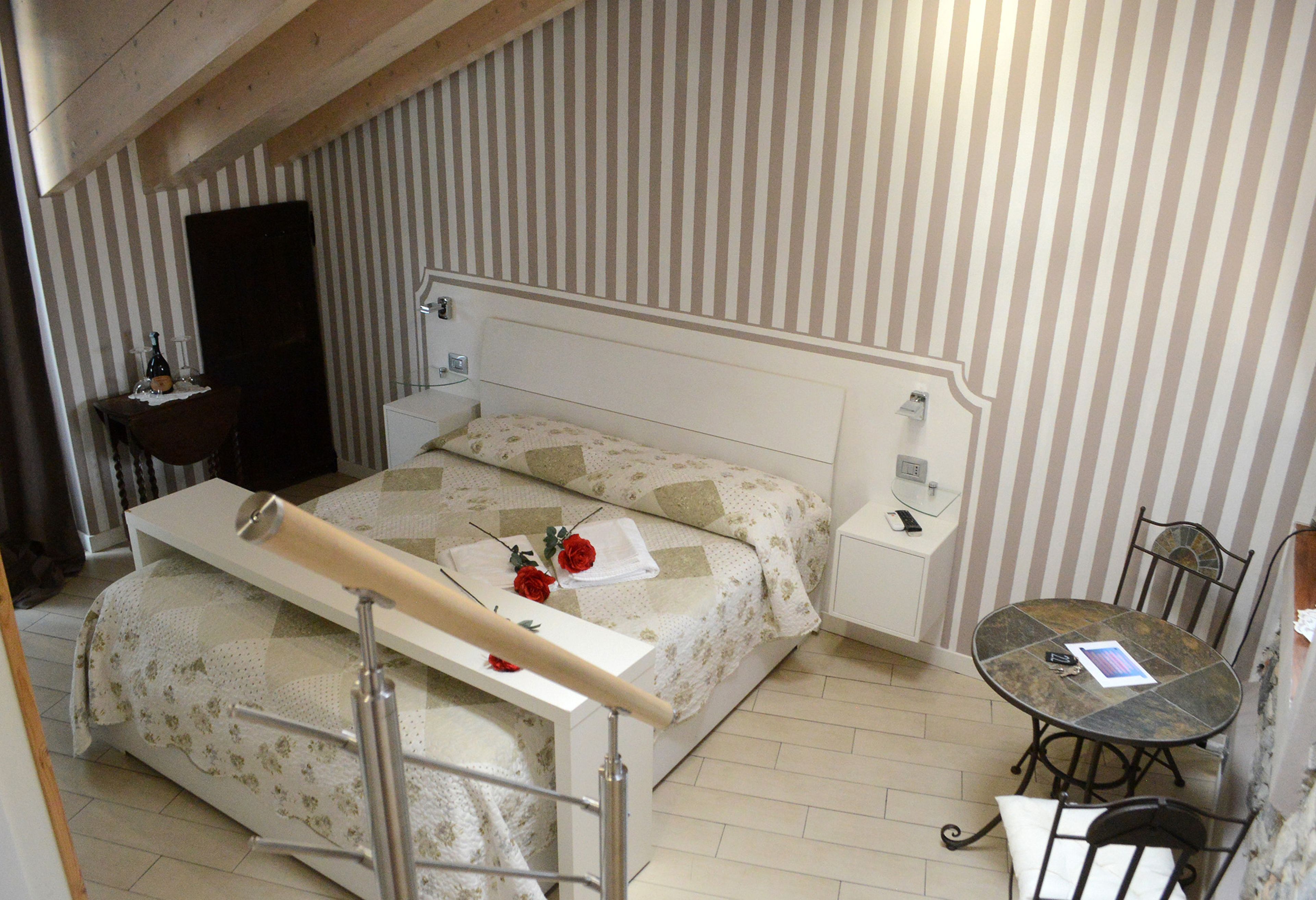 A bedroom with a bed, bedside table, and a small round table with chairs.