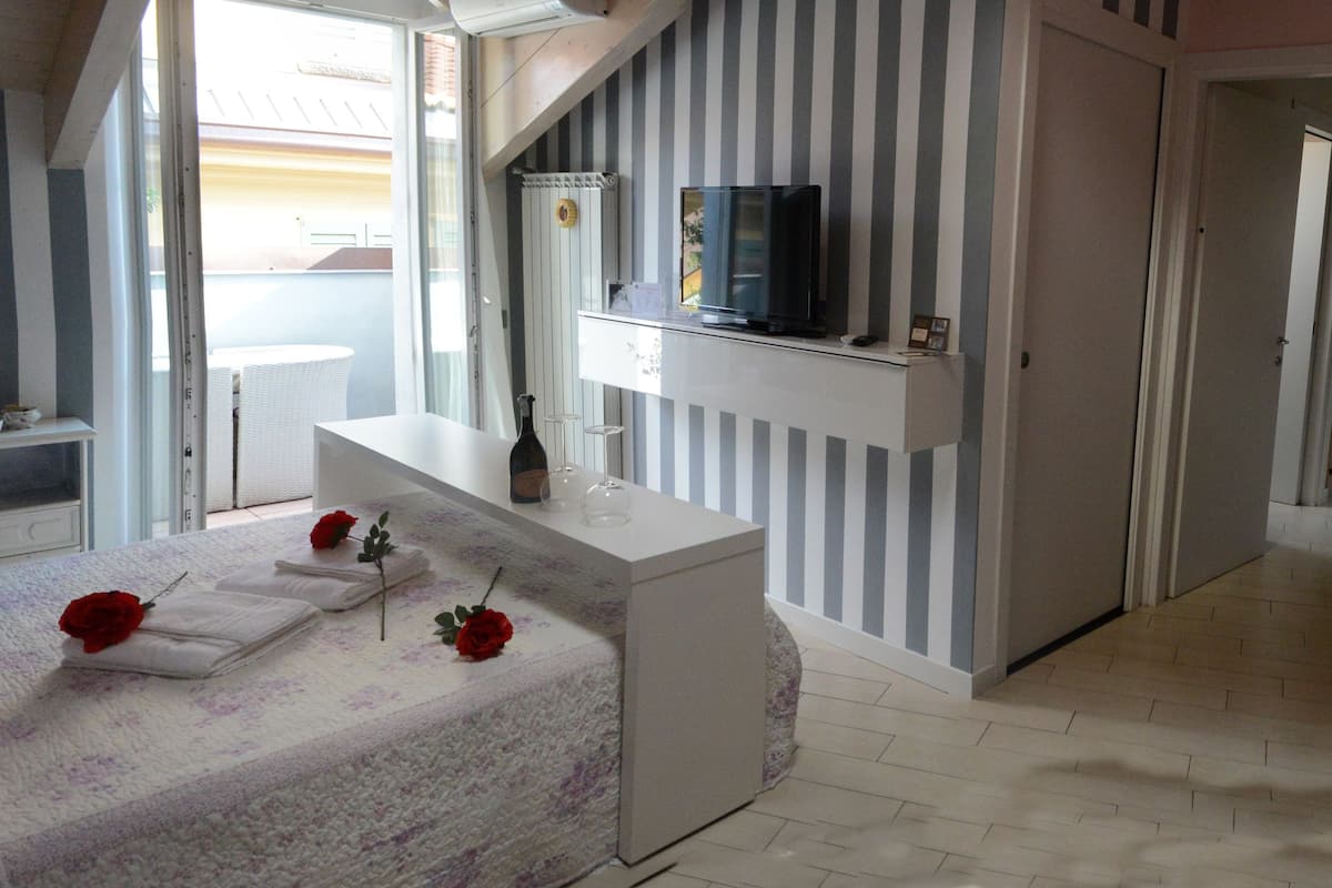 A modern bathroom with a stone wall, a large bathtub, a vanity with a mirror, and a television on the wall.
