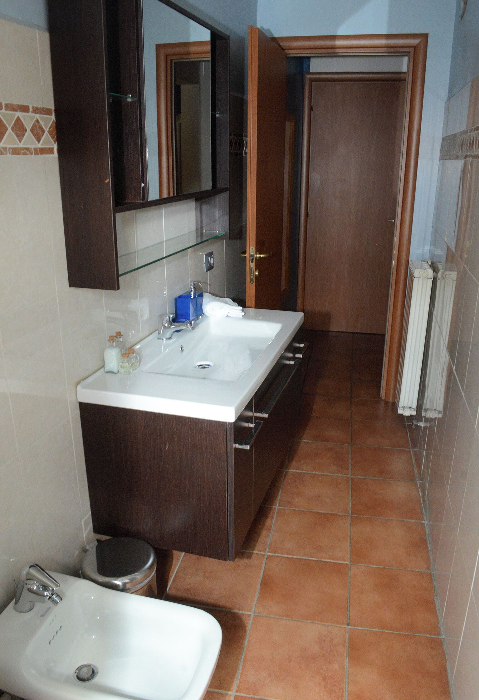 A bathroom with a double sink, a mirror, a toilet, and a shower.