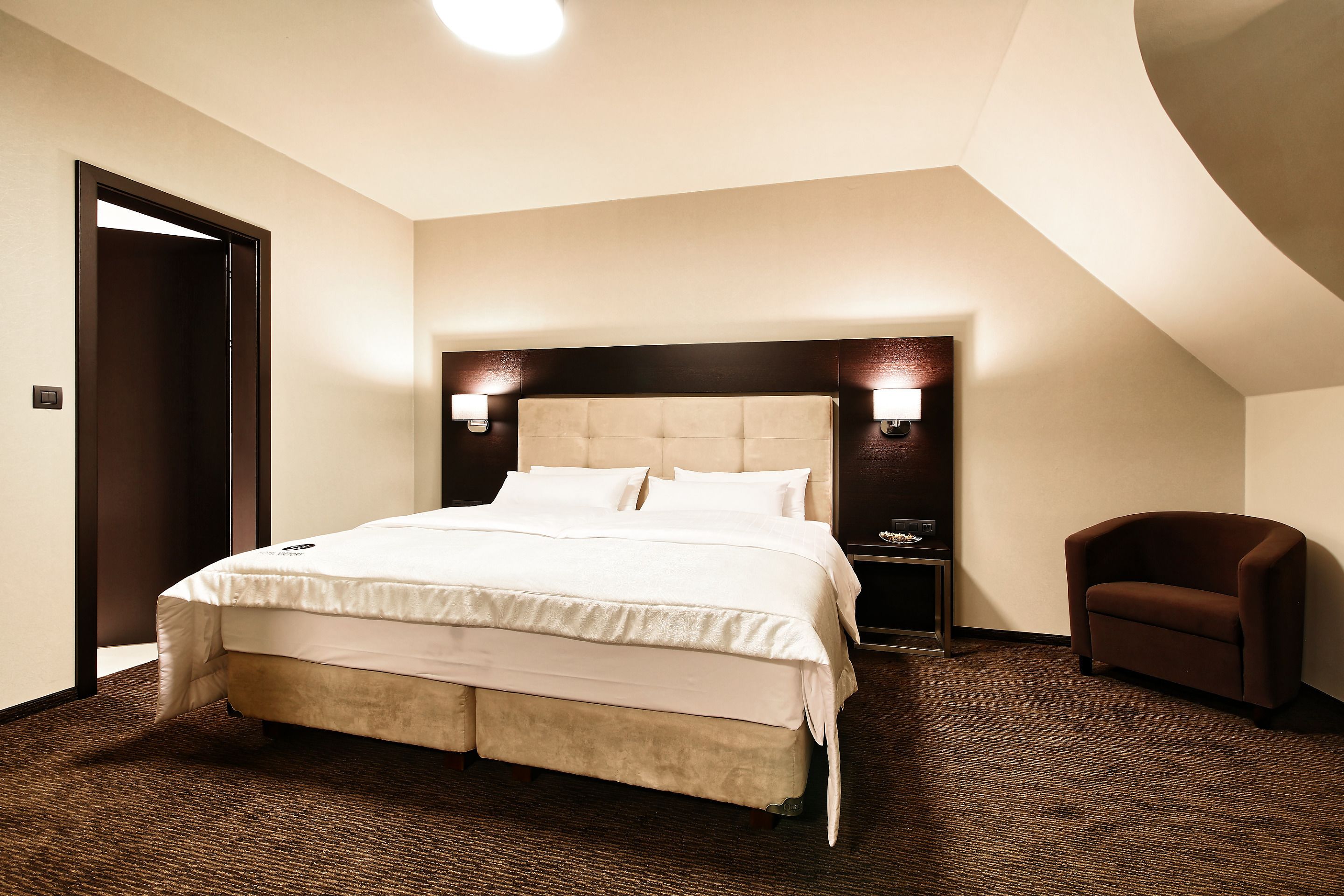 Una habitación de hotel con una cama grande, una silla y una mesita de noche.