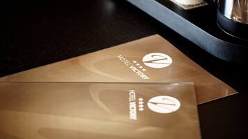 Two brown envelopes with the Hotel Victory logo on a dark surface.