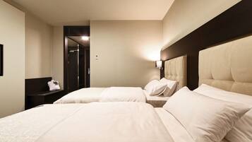 Een hotelkamer met twee bedden, een donker hoofdeinde, een nachtkastje met een lamp en een spiegel.