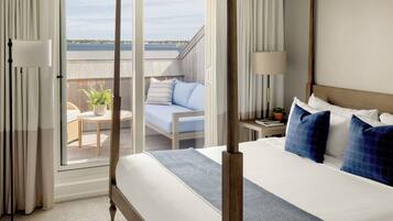 Ein Hotelzimmer mit einem großen Bett, einem Balkon mit Blick und einem kleinen Tisch mit Stuhl.