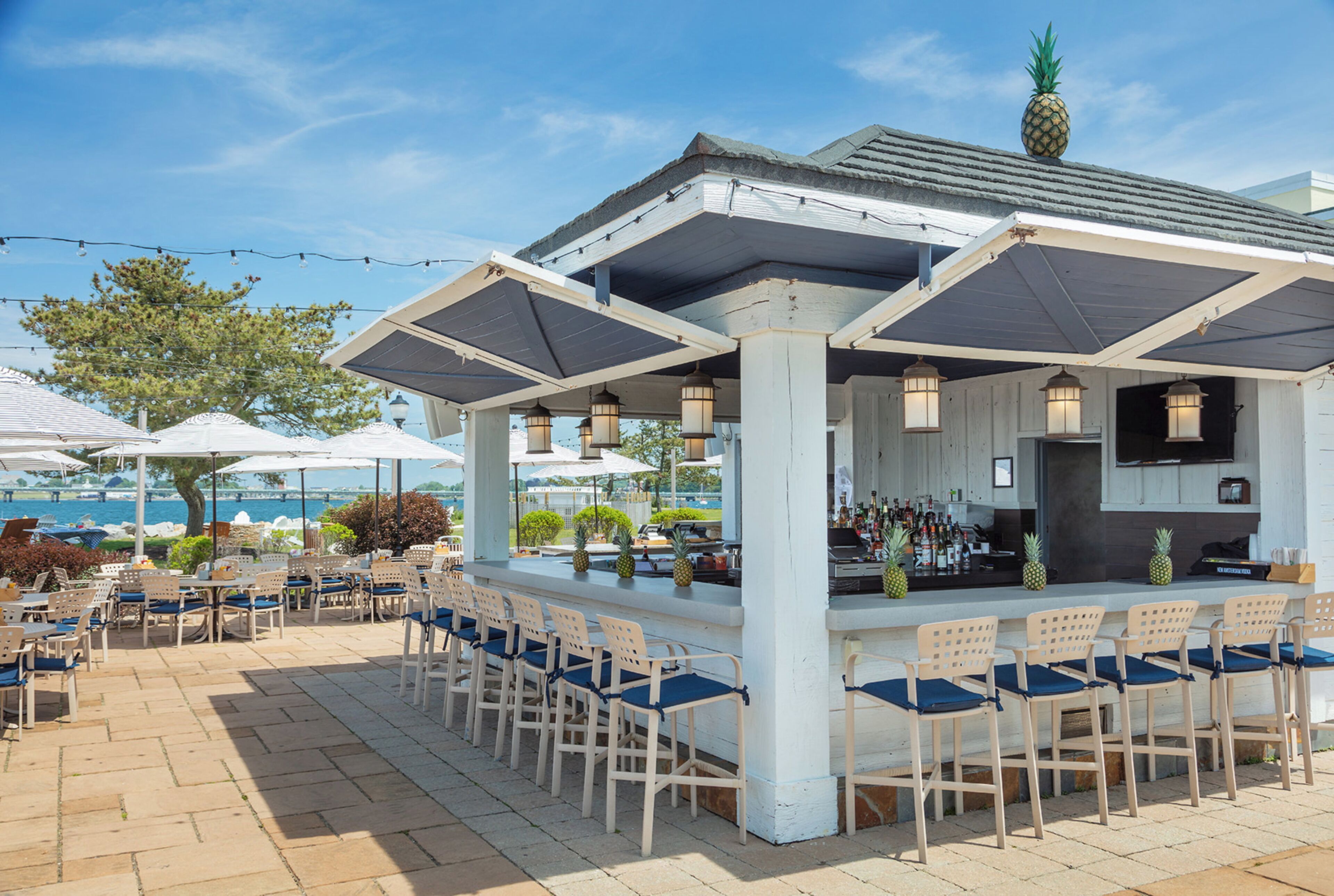An outdoor bar area with a white roof, multiple chairs, and a bar counter.