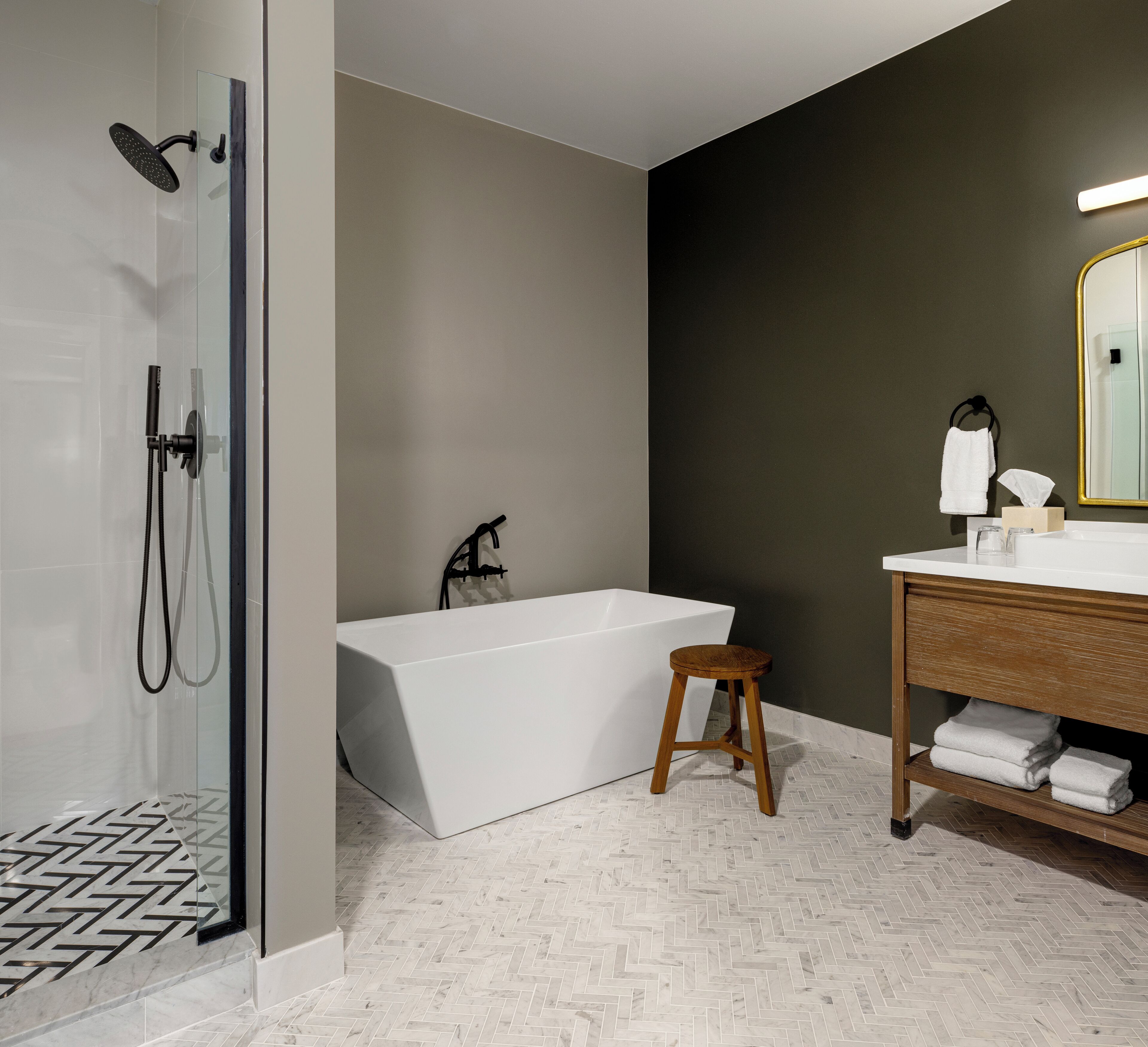 A modern bathroom with a glass-enclosed shower, a freestanding bathtub, and a wooden vanity with a mirror.