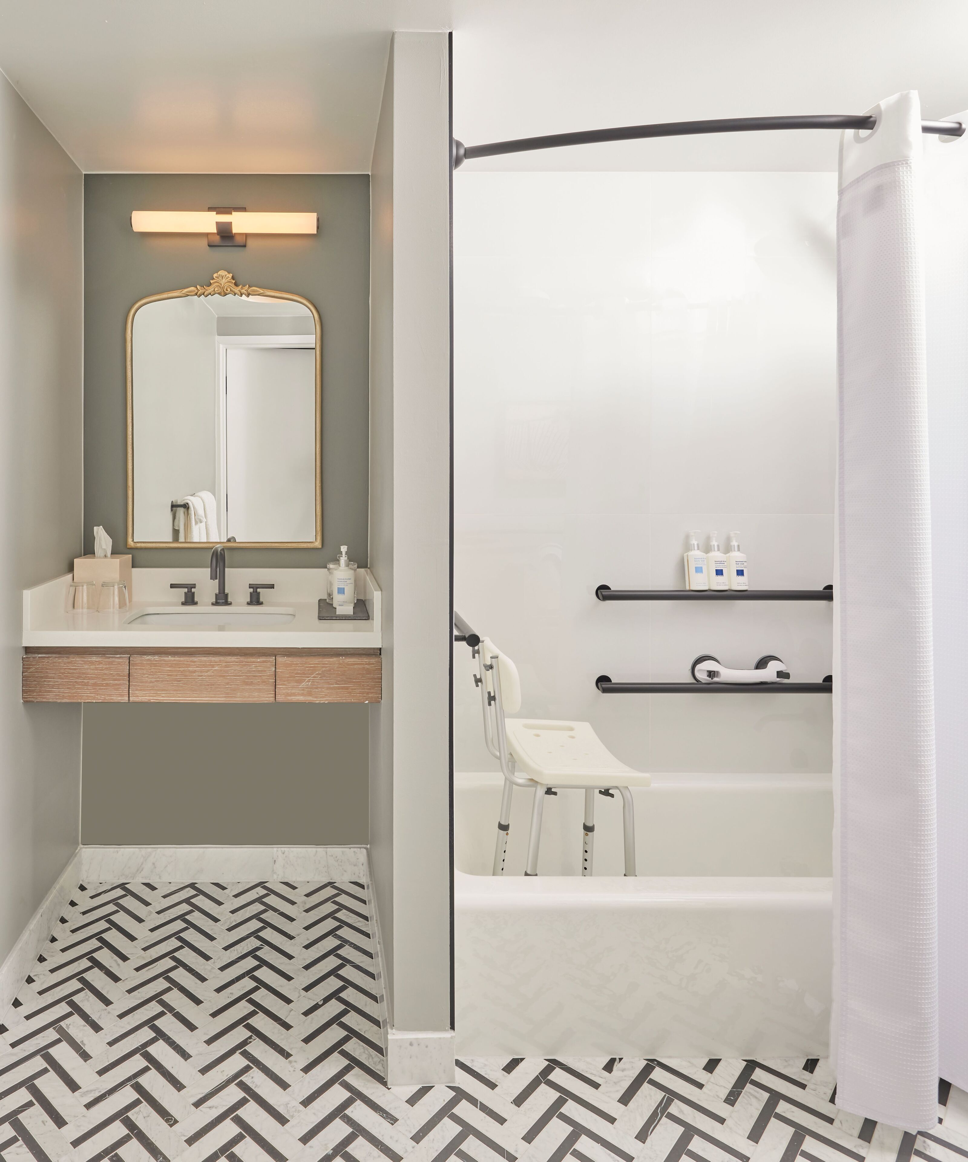 Ein modernes Badezimmer mit Fischgrätparkett, einem Waschtisch mit Spiegel und einer Badewanne mit Duschvorhang.