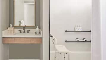 Ein modernes Badezimmer mit Fischgrätparkett, einem Waschtisch mit Spiegel und einer Badewanne mit Duschvorhang.