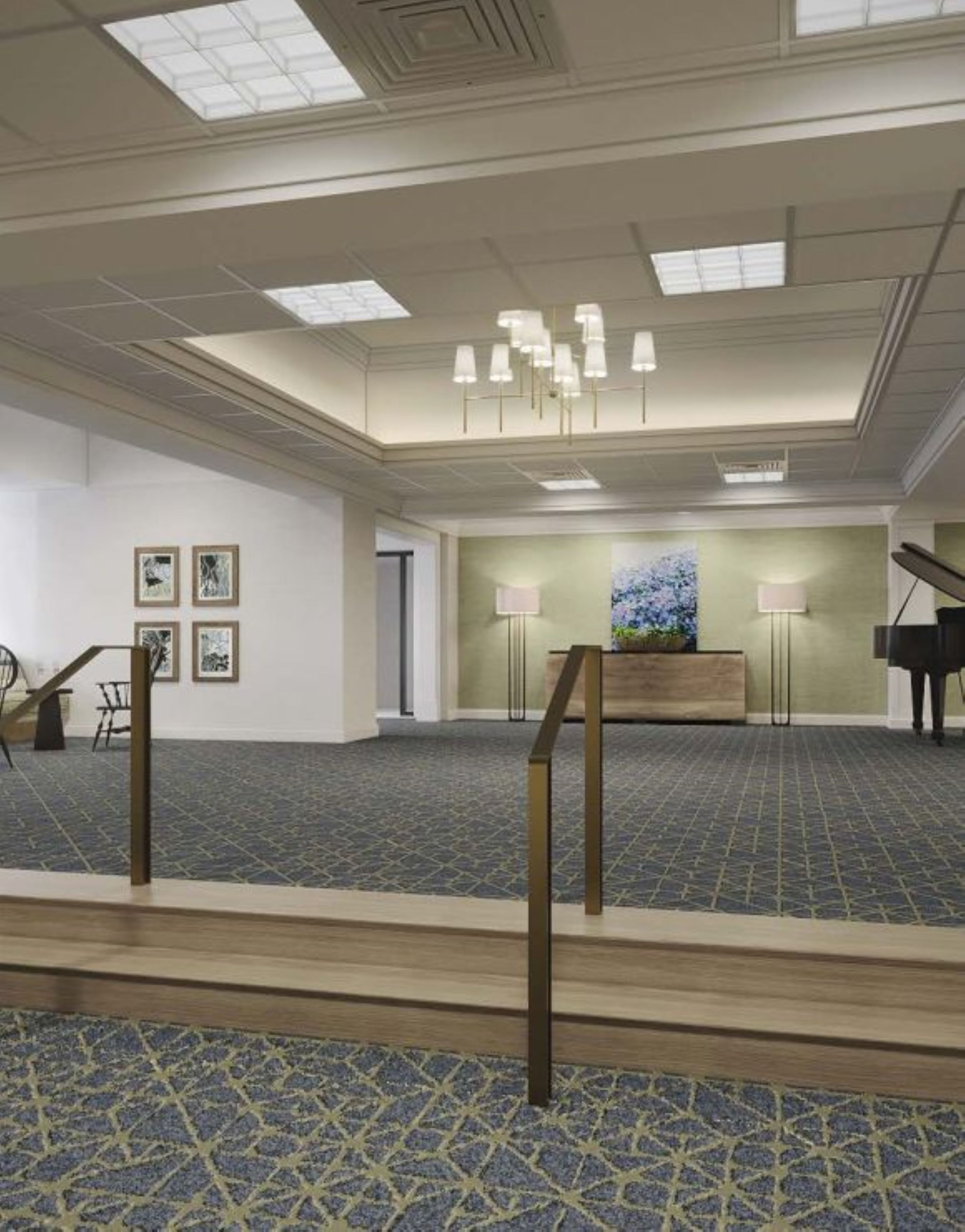 Eine großzügige Hotelhalle mit hoher Decke, einem gemusterten Teppich und einer zentralen Rezeption.