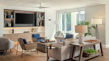 A modern living room with a flat-screen TV, comfortable seating, and a large window providing natural light.
