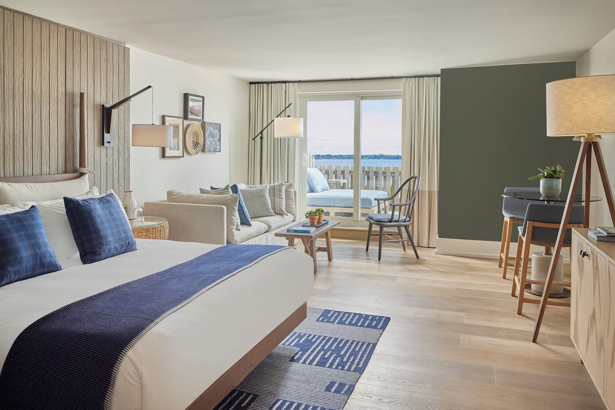 Una habitación de hotel moderna con una cama grande, un sofá, un comedor y vistas al mar.