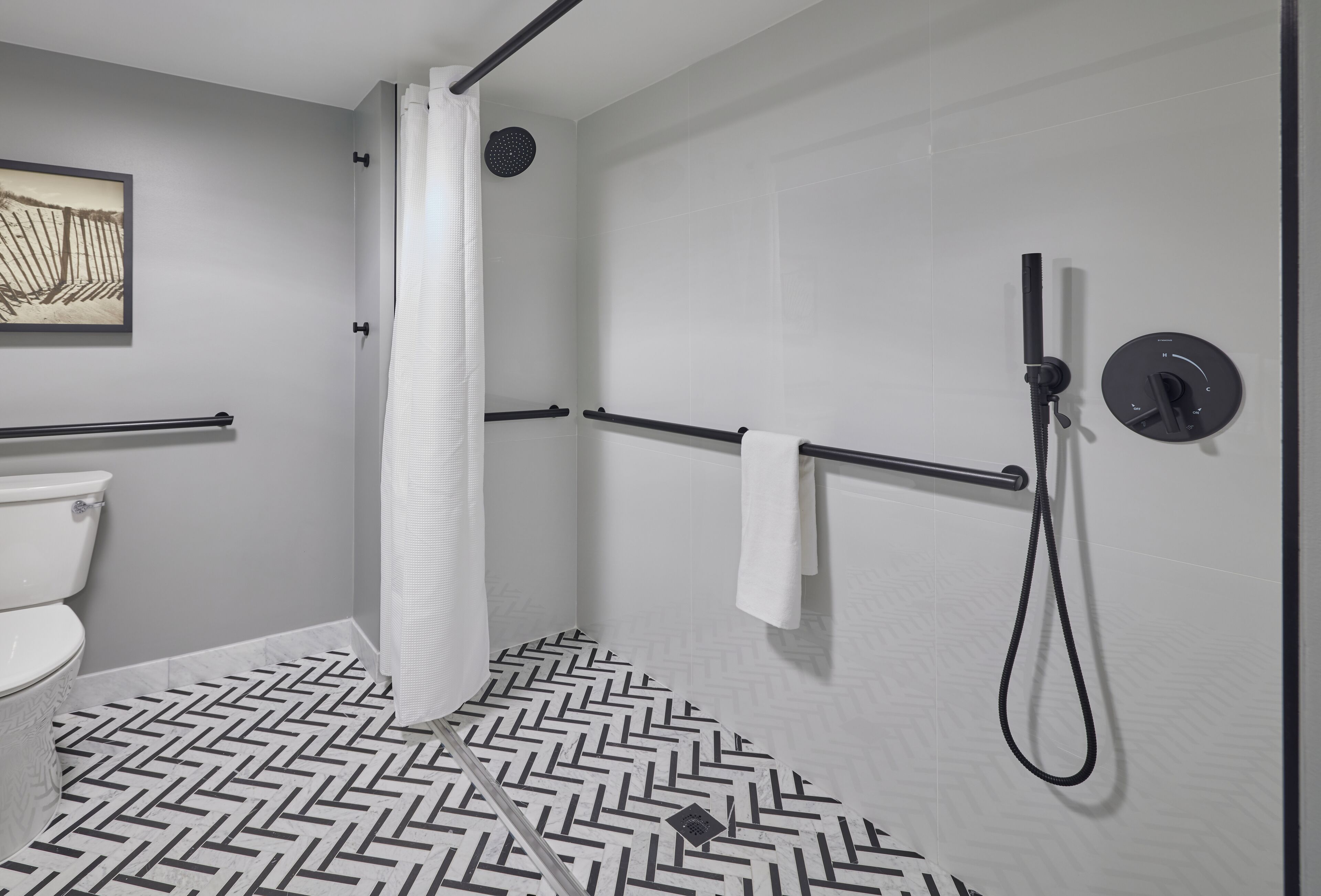 Un baño moderno con ducha, inodoro y piso con estampado de espiga.