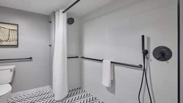 Une salle de bain moderne équipée d’une douche, de toilettes et d’un sol carrelé disposé en motif de chevrons.