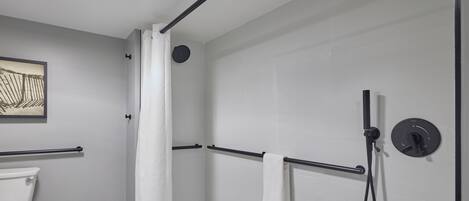 Un baño moderno con ducha, inodoro y piso con estampado de espiga.