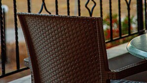 A wicker chair and a table on a balcony with a view of the sunset. - Romanos Beach Villas (Pylos-Nestoras)