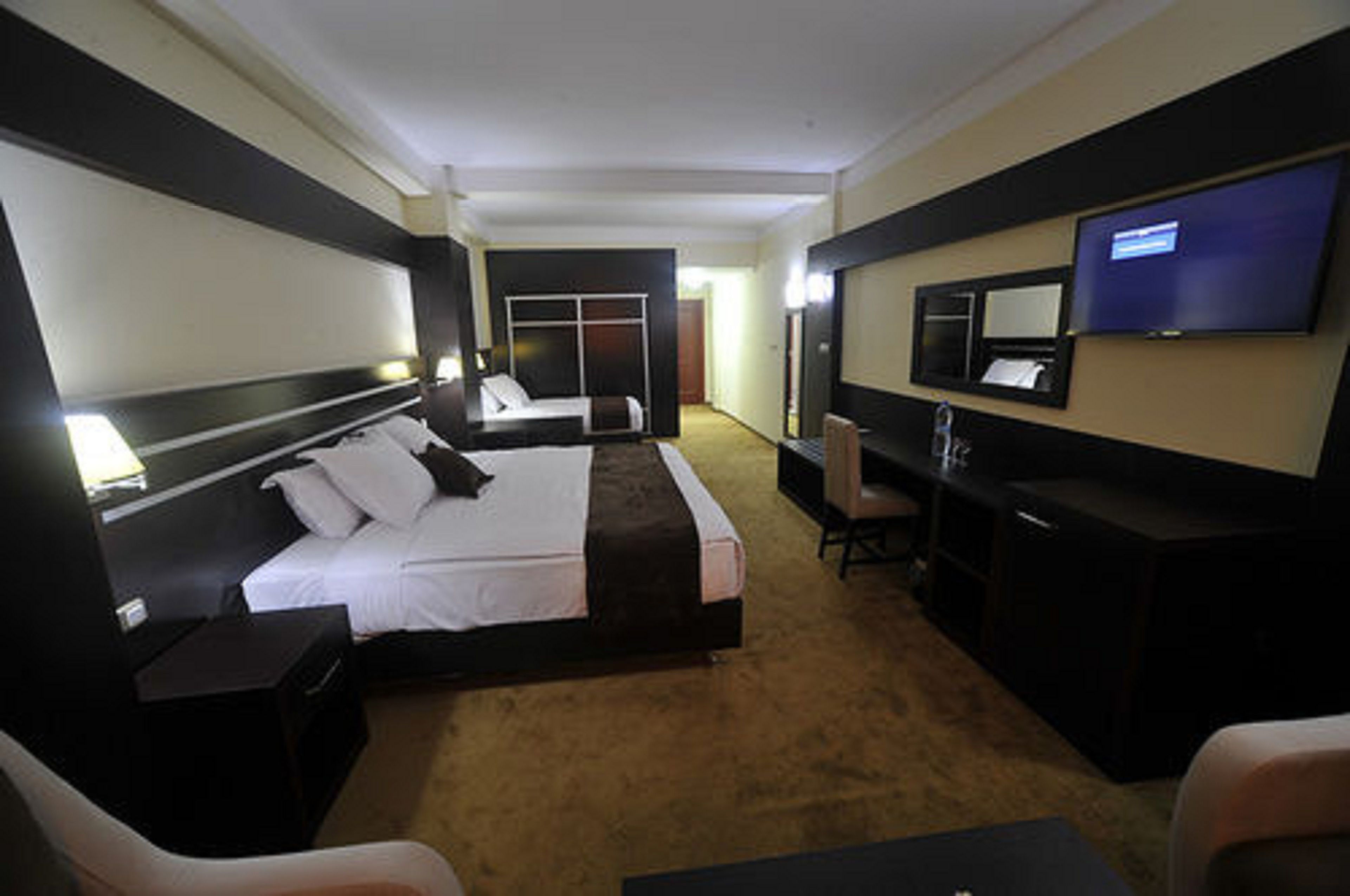 Una habitación de hotel con una cama grande, un escritorio, una silla, un televisor y un armario.