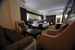 A hotel room with a bed, two armchairs, a coffee table, and a desk.