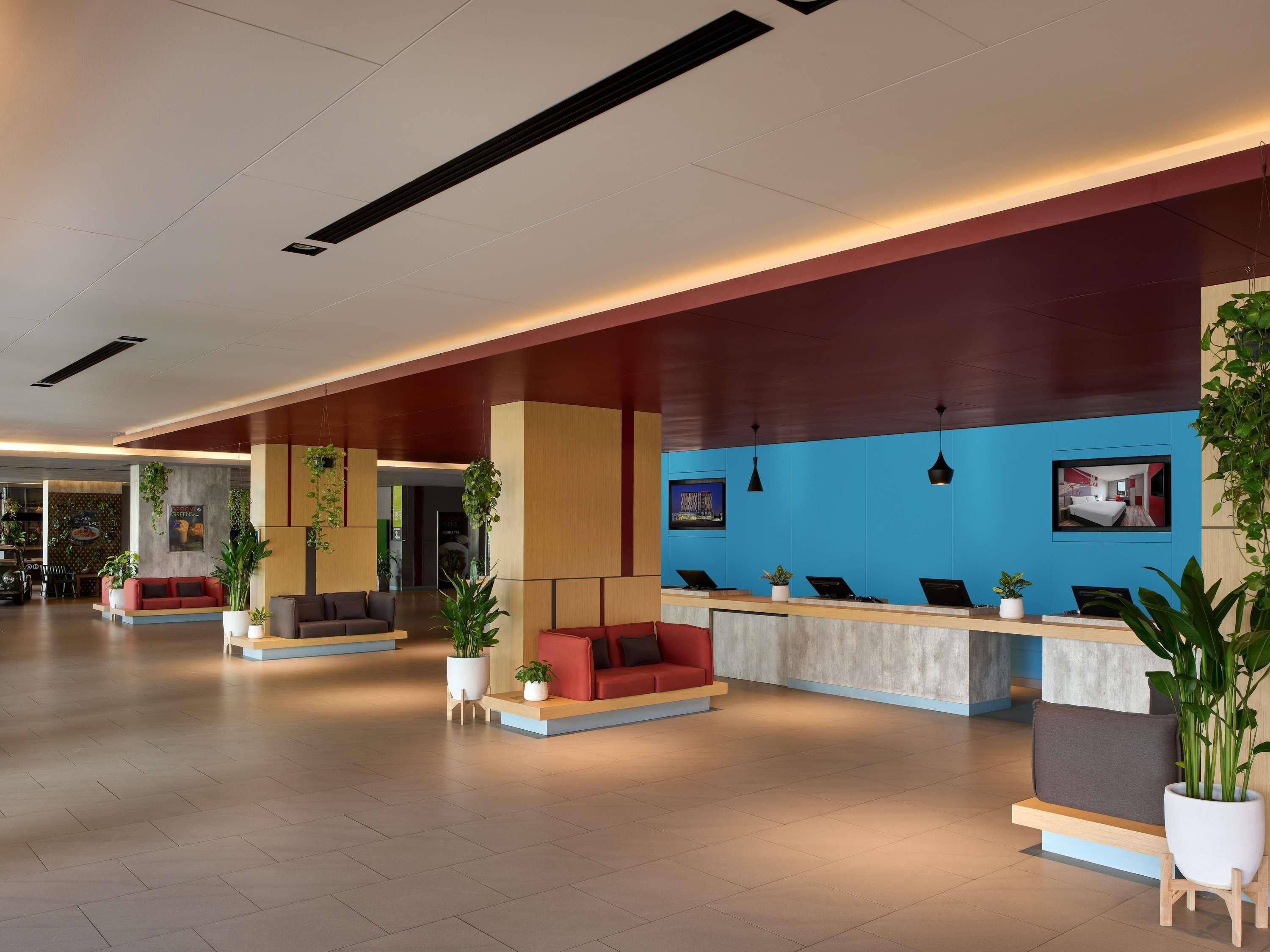 Eine moderne Hotellobby mit Sitzbereichen, einem Empfangstresen und einer großen blauen Akzentwand.