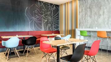 A modern dining area with booths and tables, a large abstract wall art, and a concrete accent wall.