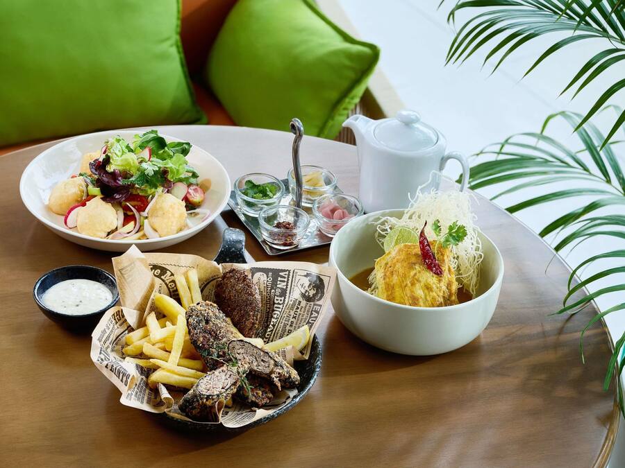 A table with a variety of dishes including a salad, noodles, fries, and meat.