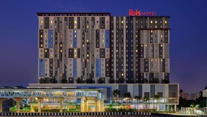 A multi-story hotel with a modern design, featuring a prominent 'ibis HOTEL' sign at the top. - ibis Bangkok IMPACT (Pak Kret)
