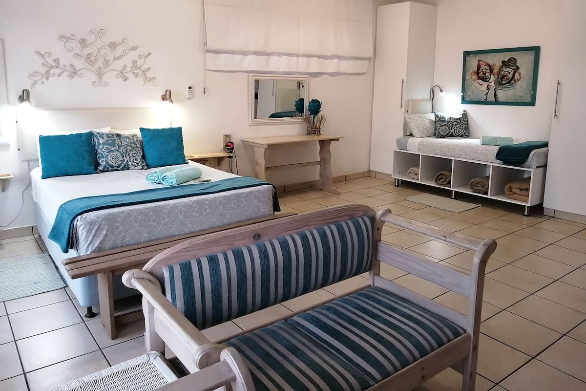 A bedroom with a bed, bedside tables, a dresser, a chair, a mirror, and a painting.