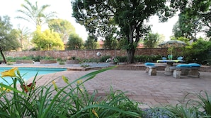 Patio trasero con piscina, terraza de ladrillo y mobiliario exterior.