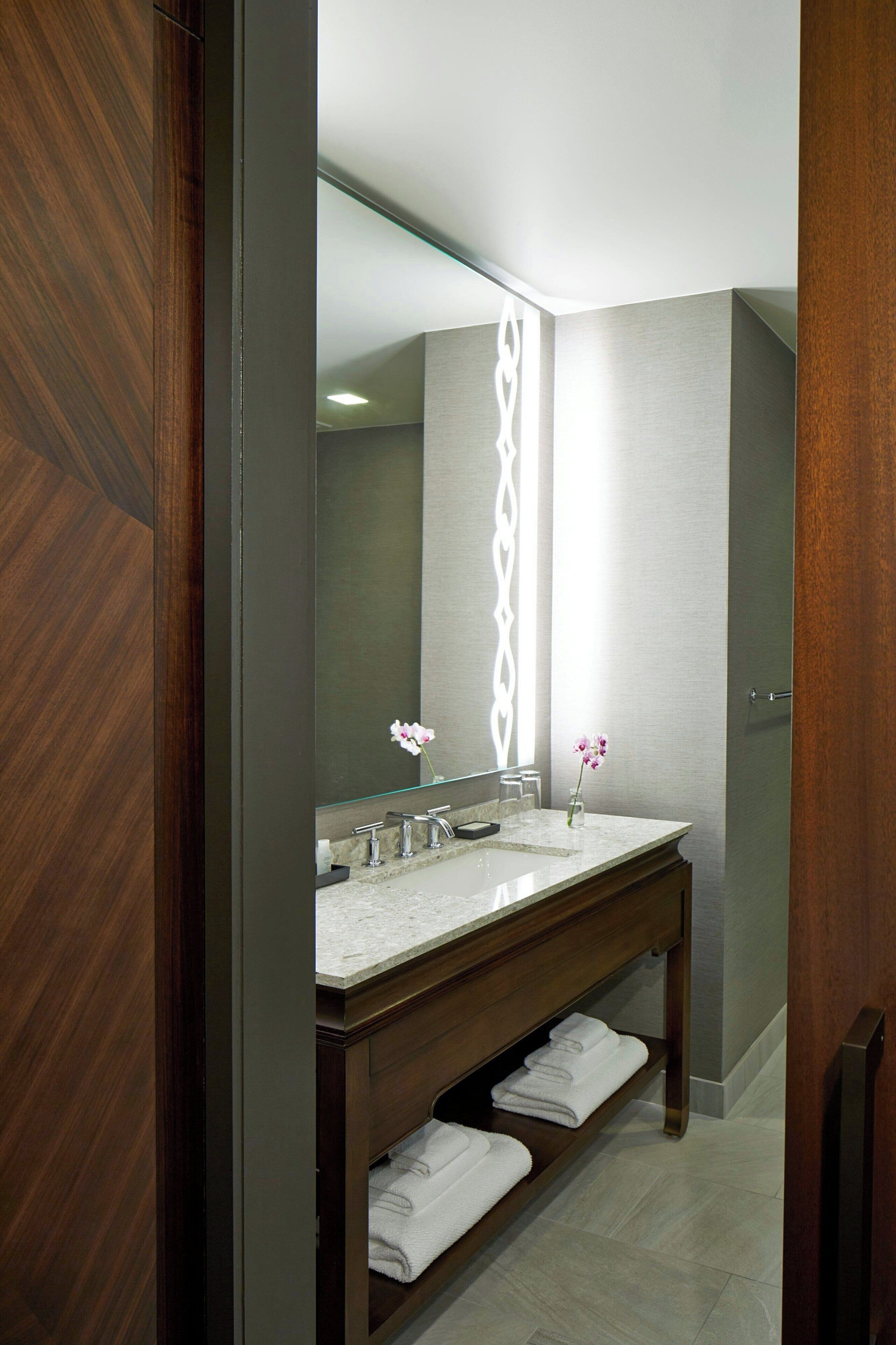 Une salle de bain moderne avec un meuble-lavabo en bois, un grand miroir et une étagère à serviettes.