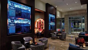 A modern lobby with comfortable seating, large digital displays, and a glass entrance. - Renaissance Dallas at Plano Legacy West Hotel (Plano)