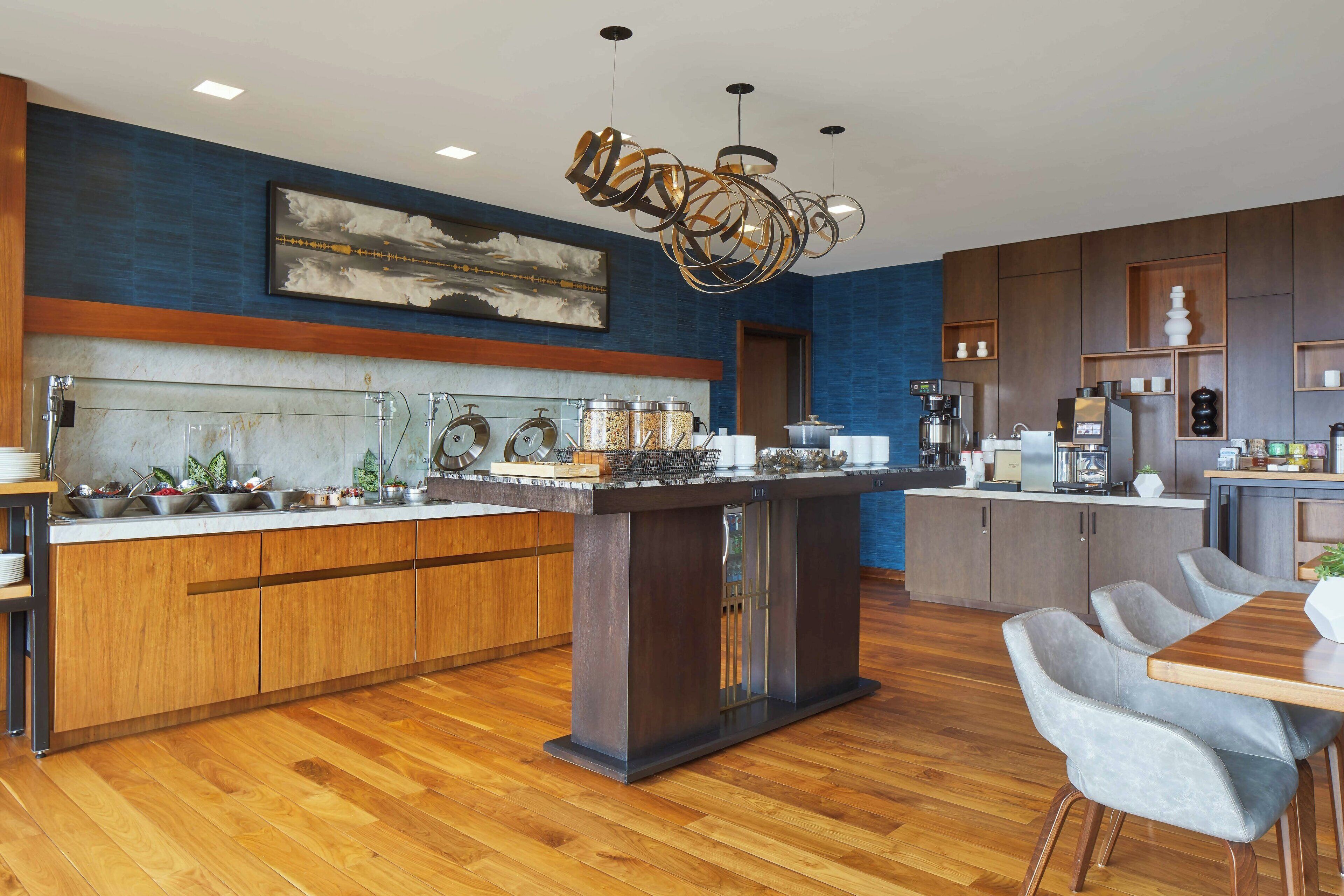 Una cocina moderna con una isla central, armarios de madera y una pared azul decorativa.