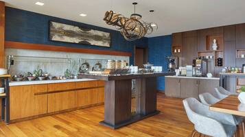 Una cocina moderna con una isla central, armarios de madera y una pared azul decorativa.
