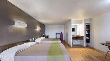 A hotel room with two beds, a bathroom with a sink, and a small table.