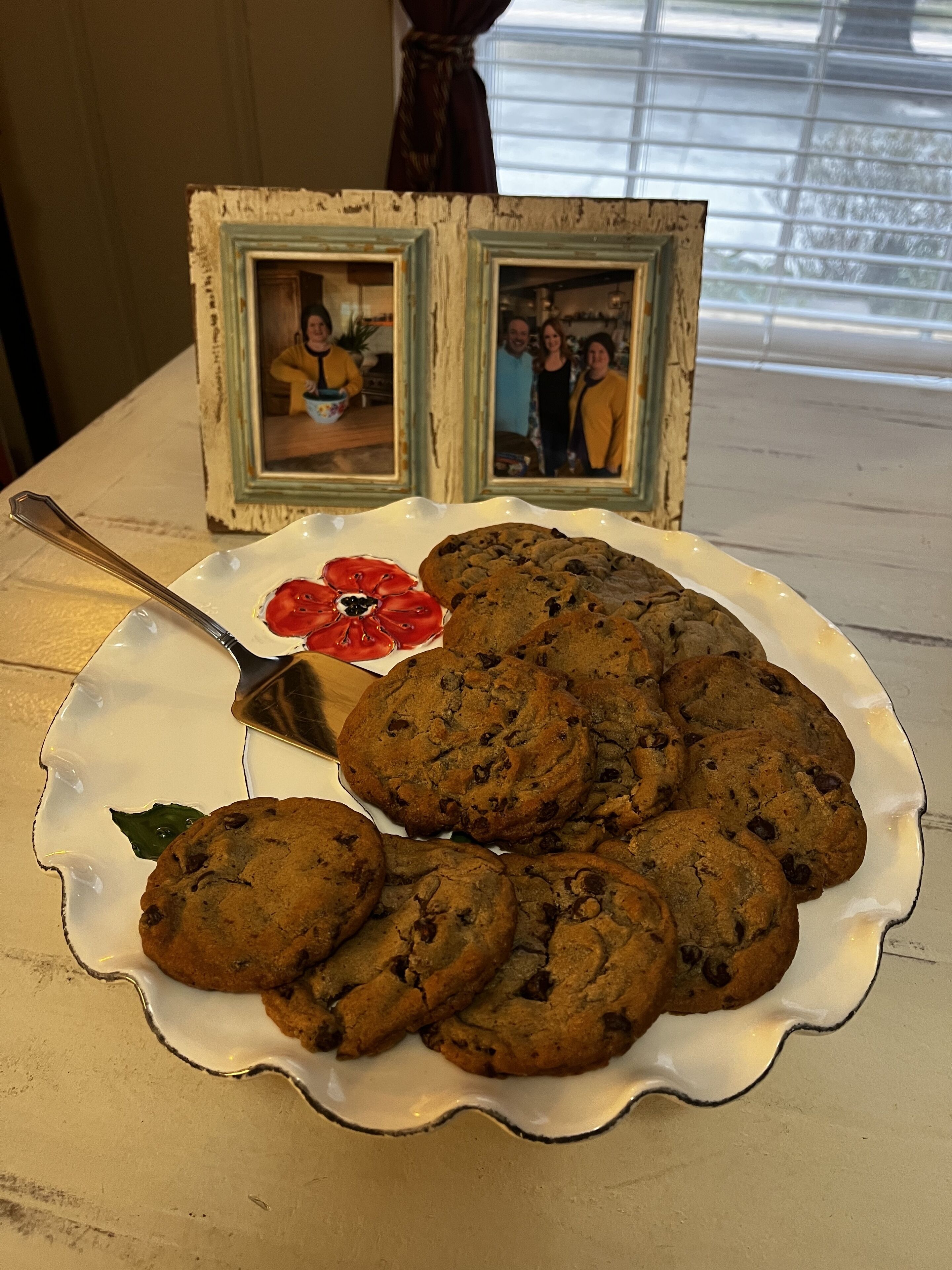 Une assiette de biscuits aux pépites de chocolat est posée sur une table, avec un cadre décoratif en arrière-plan.