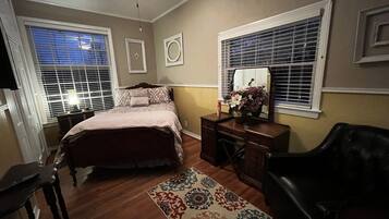 A bedroom with a bed, dresser, chair, and a ceiling fan.