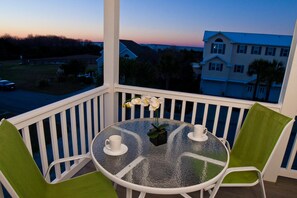 A balcony with a glass table, two chairs, and a small potted plant.